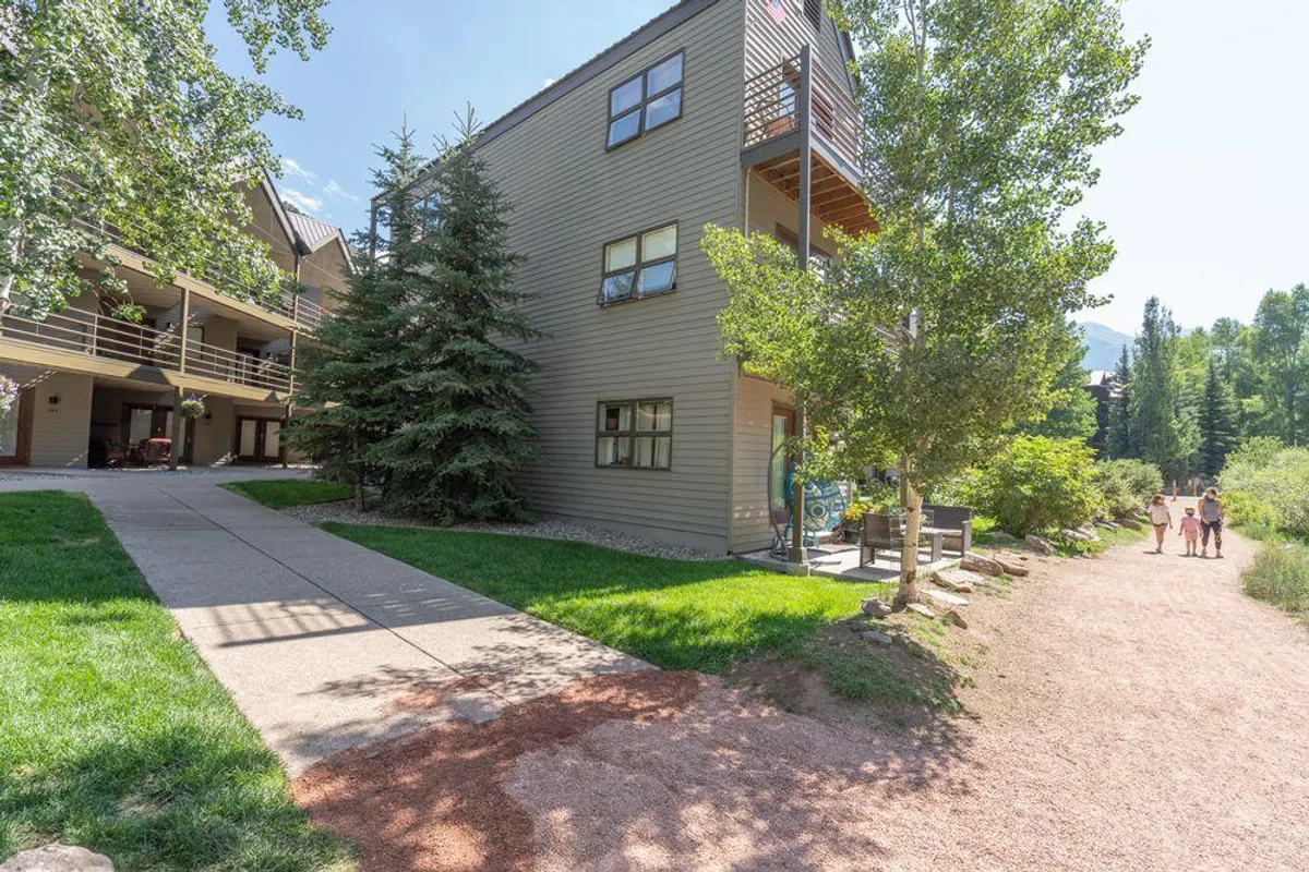 A tranquil exterior shot showcasing a multi-story building surrounded by greenery and a walking path. The inviting scene suggests easy access to outdoor spaces, ideal for strolls and relaxed family exploration.